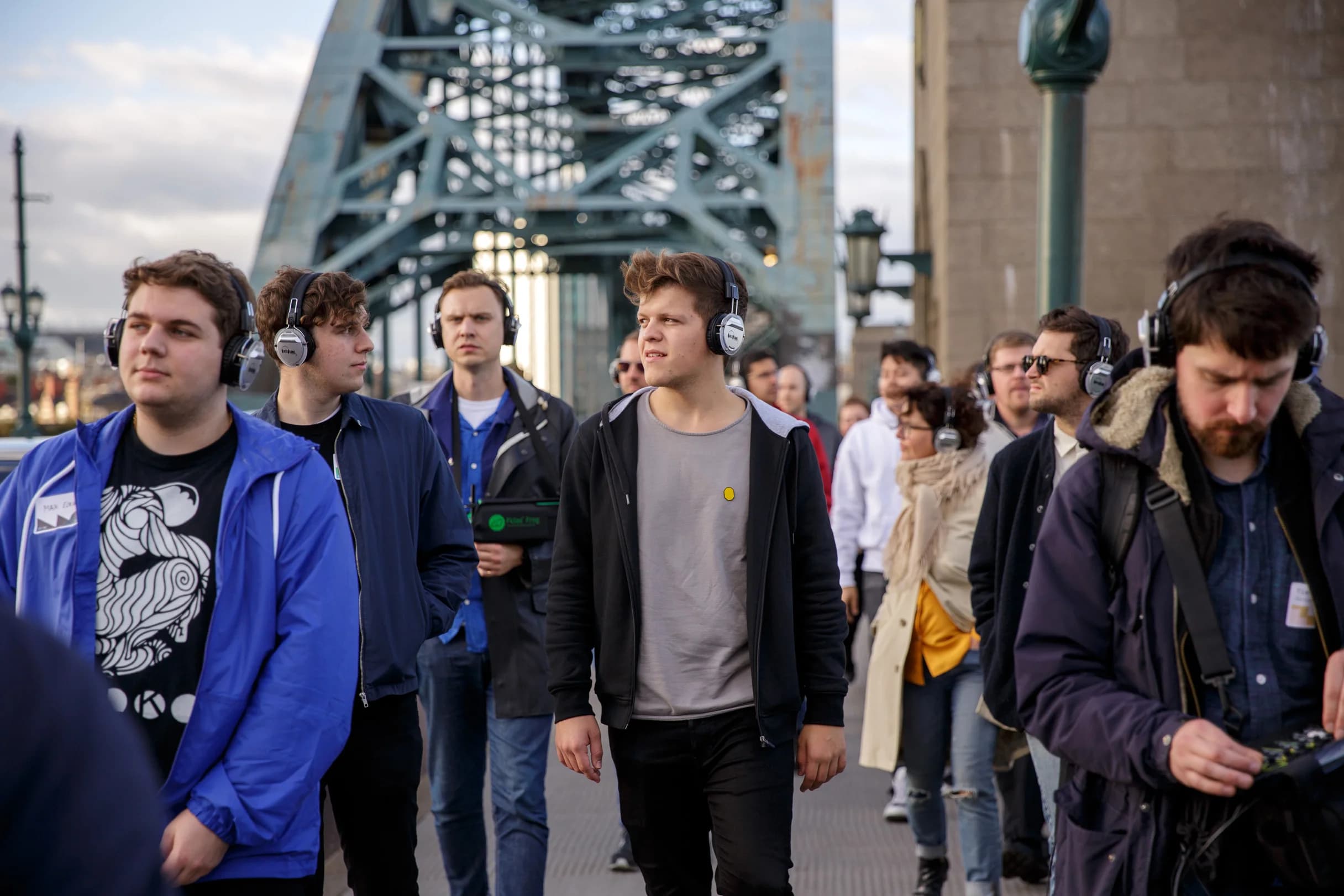 A group walks across a bridge wearing headphones.