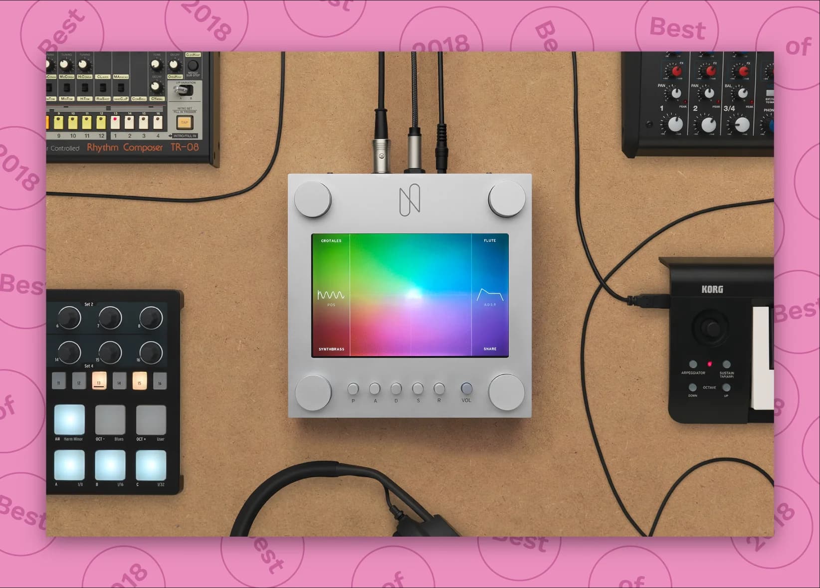 Top view of electronic music equipment including synthesizers, drum machines, a small mixer, and headphones arranged on a tan surface.