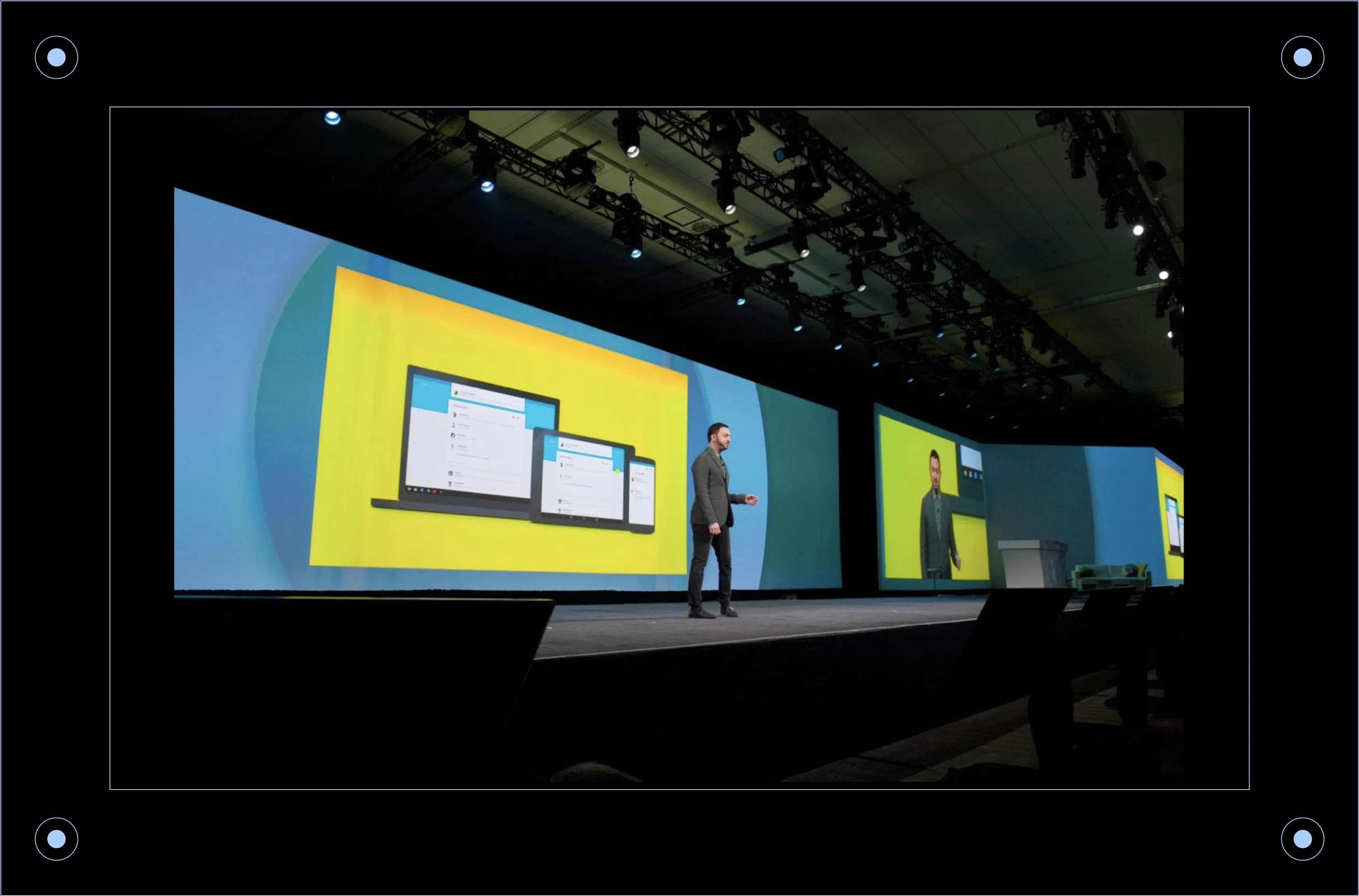 Matias Duarte gestures toward large screens displaying messaging apps on a stage at a tech conference.