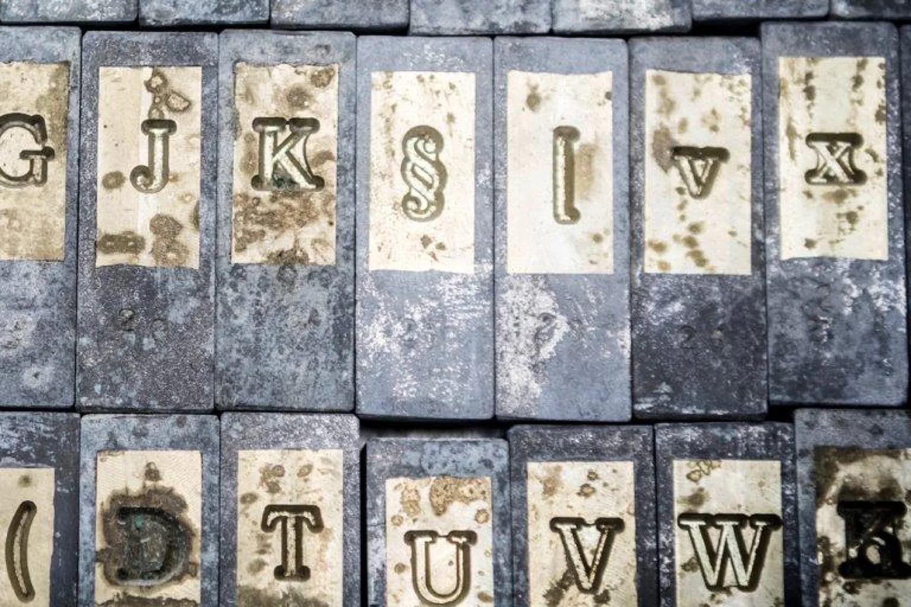 Vintage printer's blocks spell out random letters of the alphabet. Each metal block has a worn, distressed look.