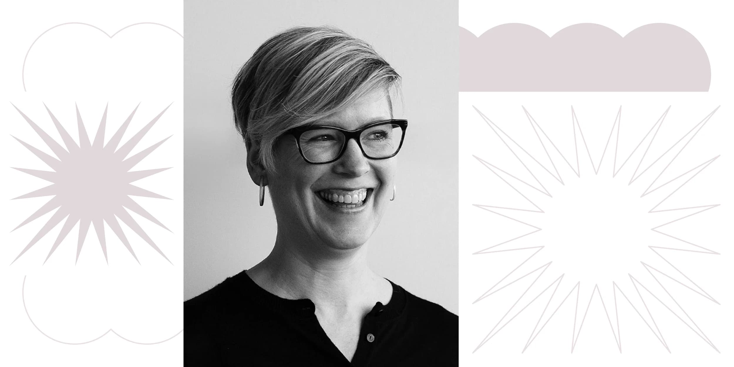 Black and white headshot of a smiling person wearing glasses, against a light purple background.