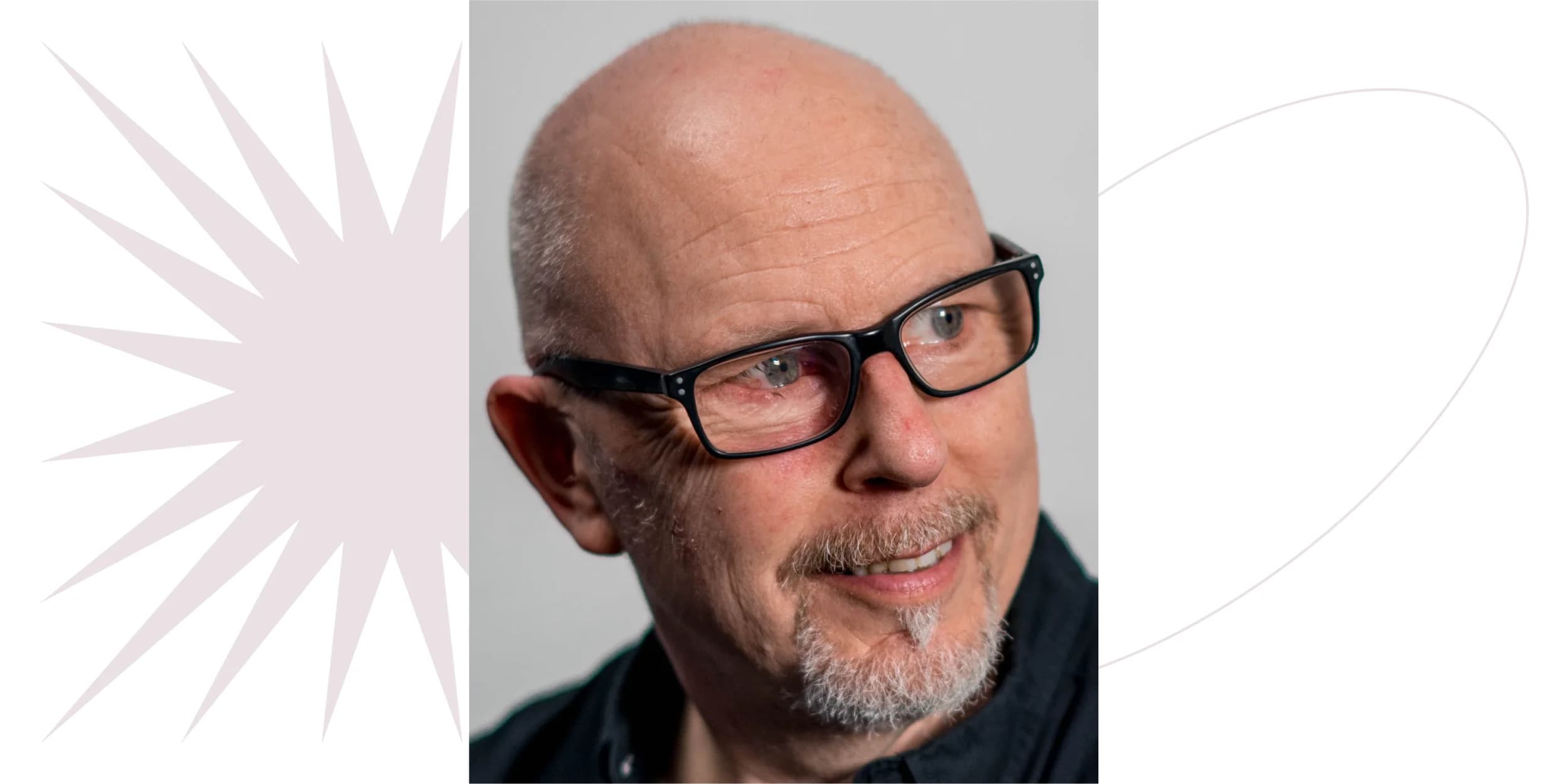 Close-up of smiling, balding man with glasses and graying goatee, looking off to the side.