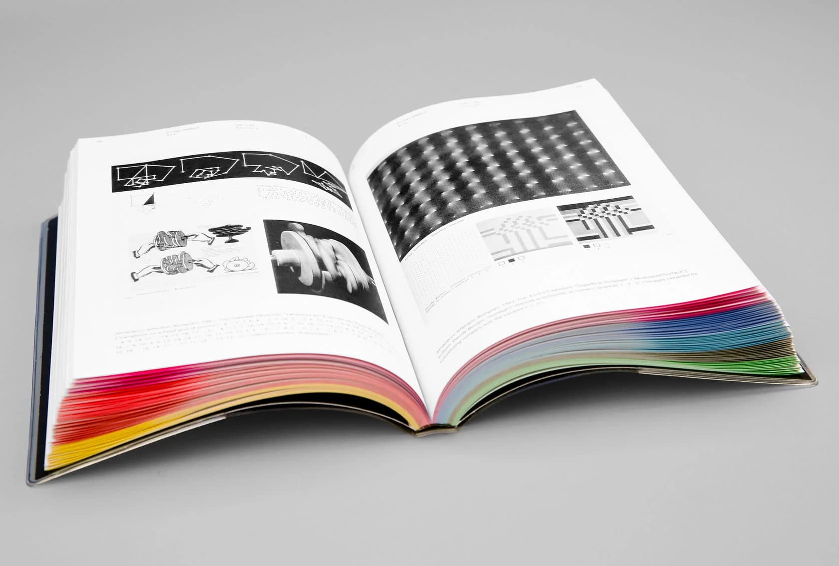 Ppen book displays graphic design elements, including geometric shapes, black-and-white patterns, and a colorful page edge.