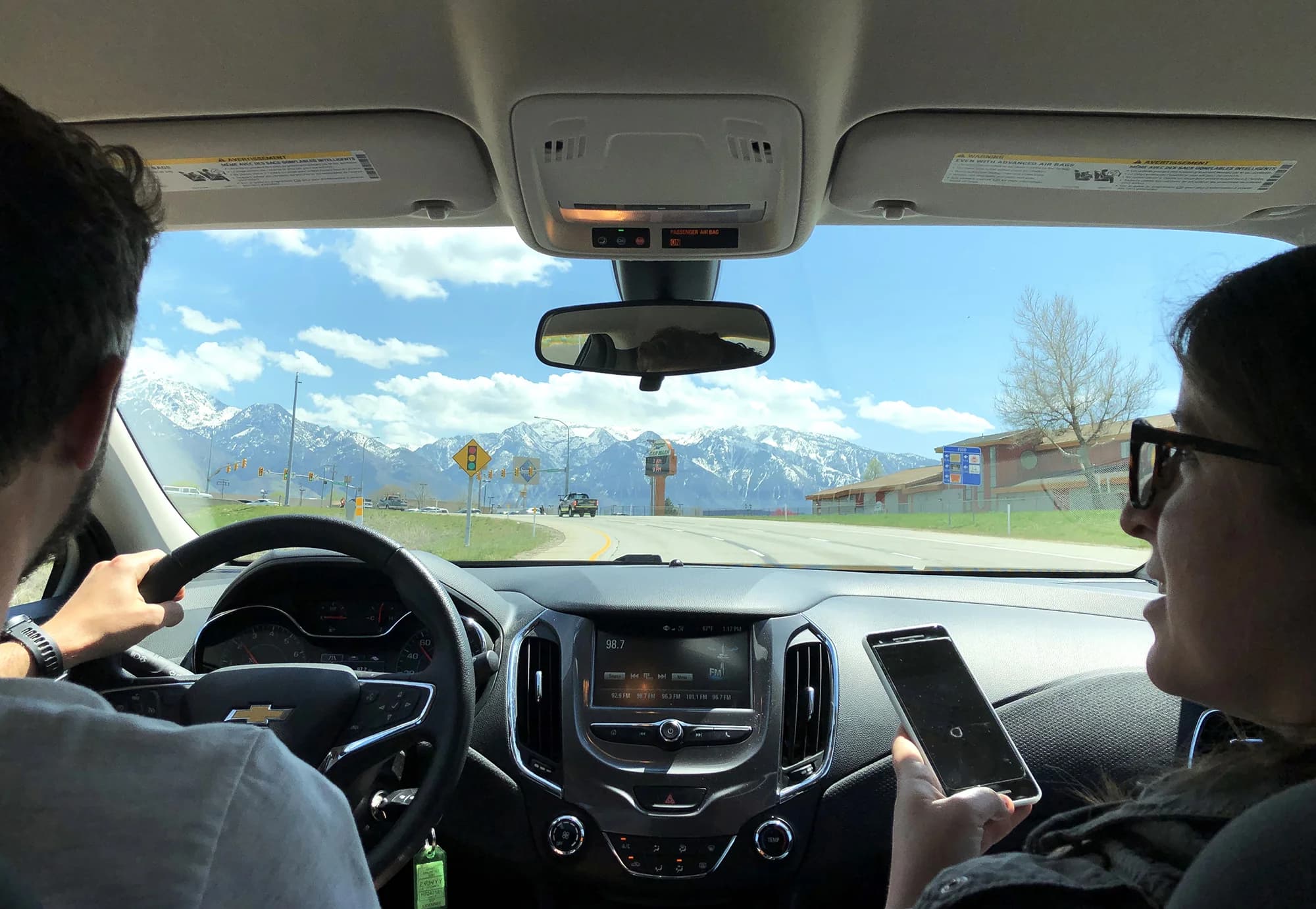 Interior of a car driving through Utah valley, snow-capped mountains rise in the distance.