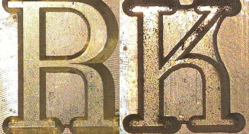 Close-up of engraved metallic letters "R" and "K." The "R" is raised; the "K" is indented.