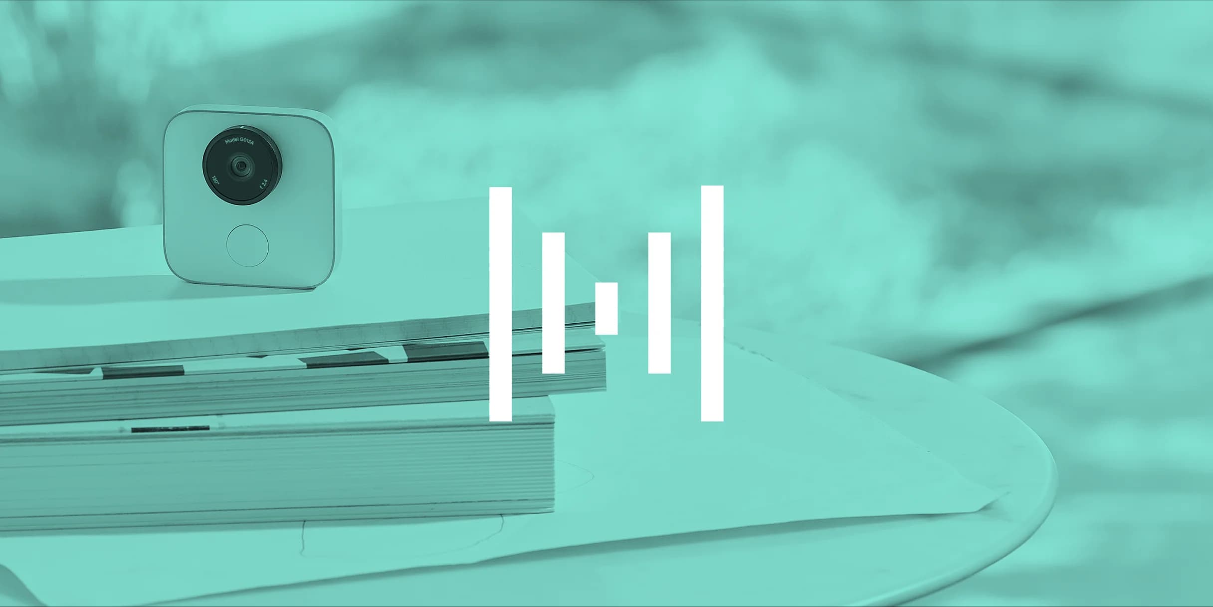 A teal-tinted photo of a small square camera resting on a stack of papers and magazines.