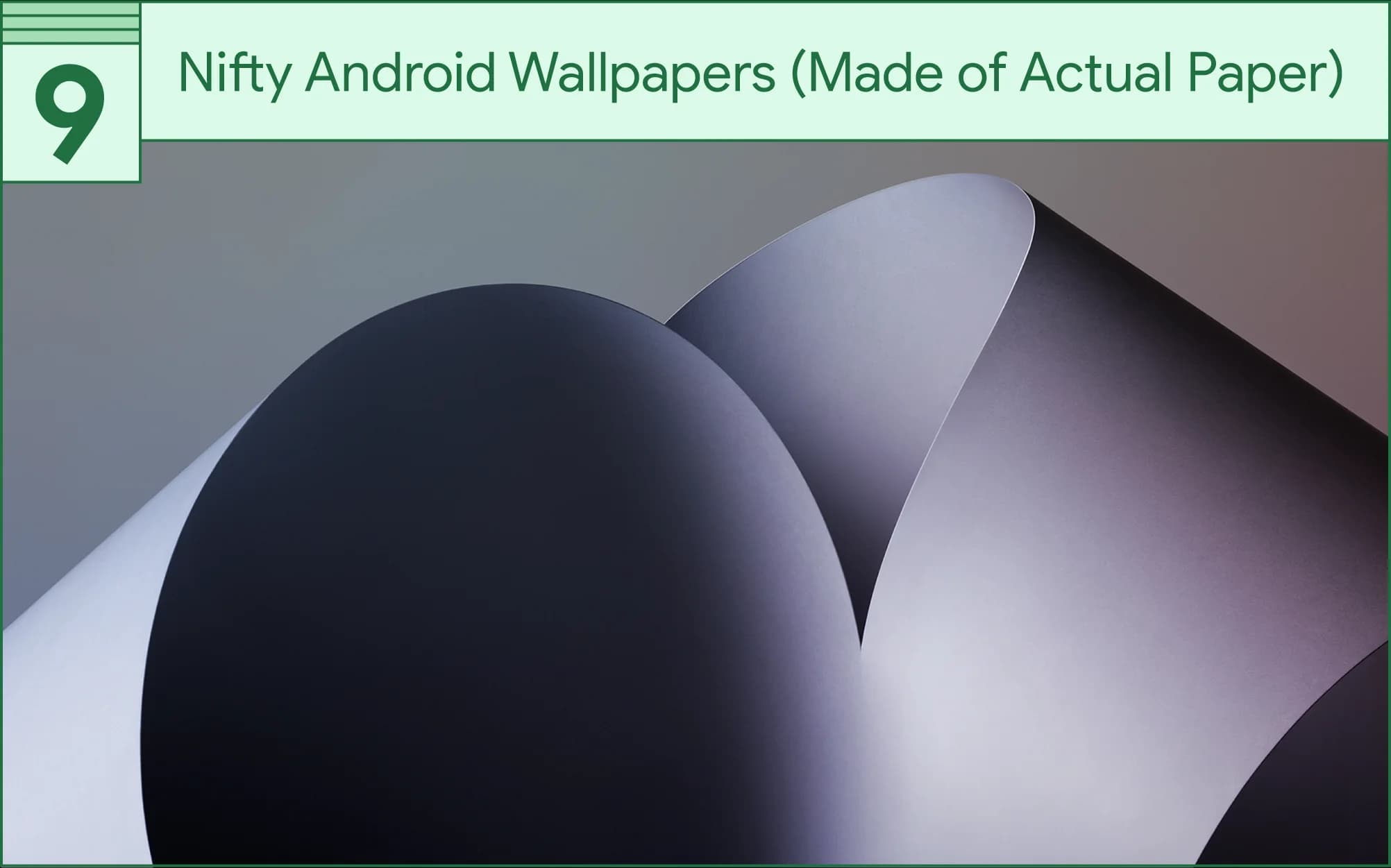 Curved sheets of gray and white paper overlap, creating abstract shapes and shadows.