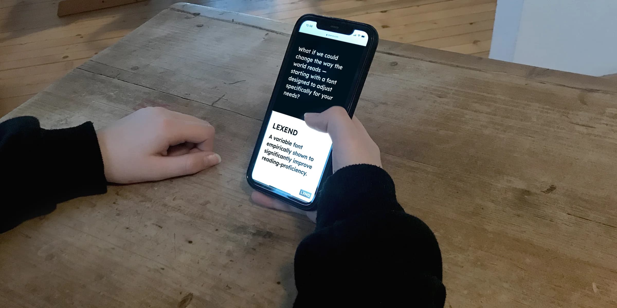 Hands hold a phone displaying information about Lexend, a variable font designed to improve reading proficiency.