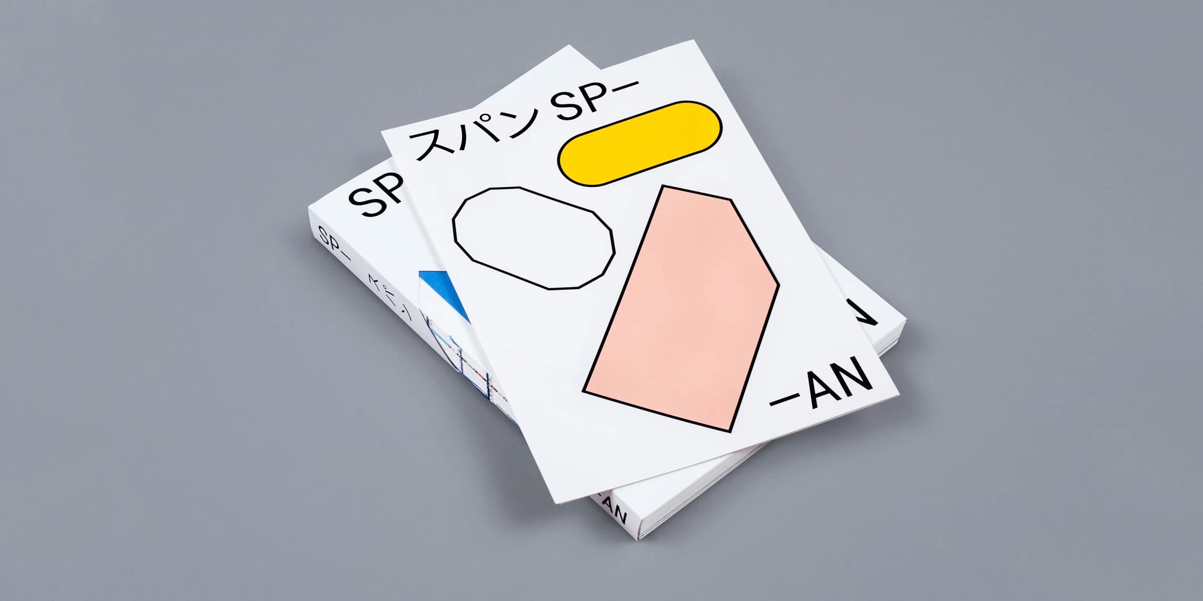 White book cover with geometric shapes—an octagon, oval, and hexagon—in black, yellow, and light red. Japanese characters and “SP-AN” are also on the cover.