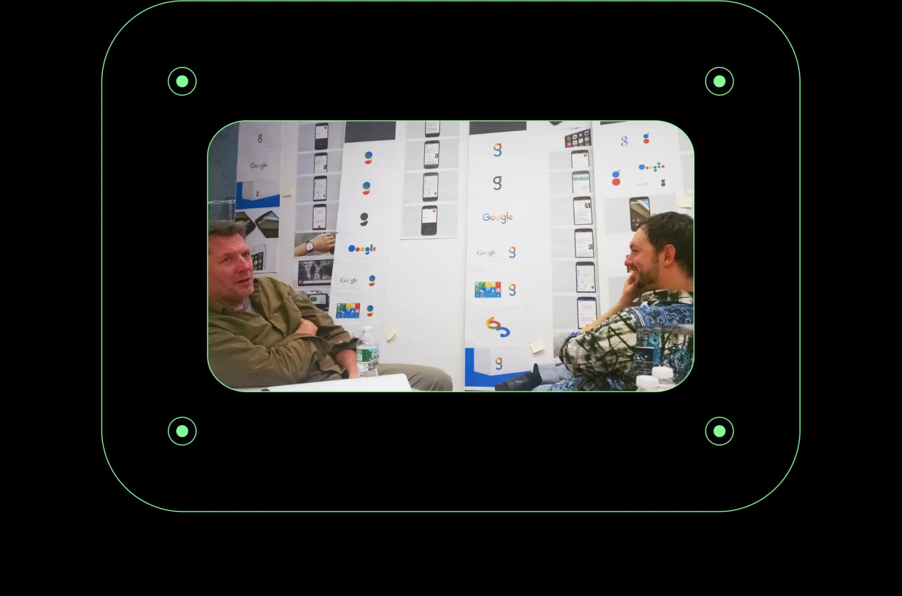 Two men in front of large paper print outs of potential Google logos.