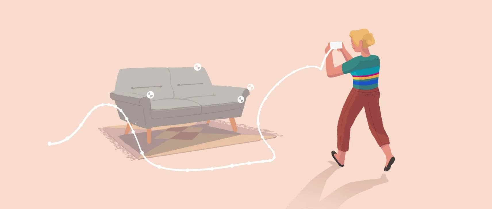 A person uses augmented reality to visualize a gray loveseat and patterned rug in a room with a pale pink background.